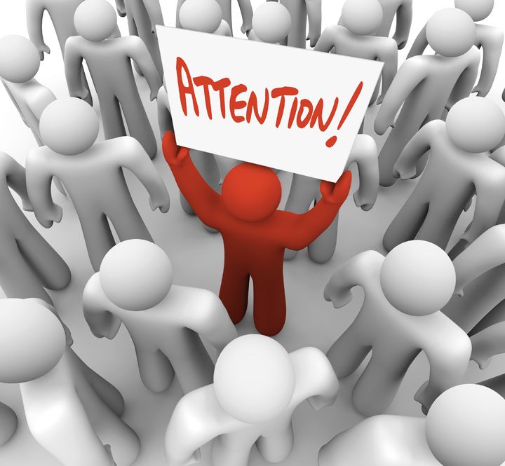 9748746 - a red person stands out in a crowd holding a sign reading attention,...